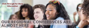 About four or five college students at a table watching something with smiles on their faces