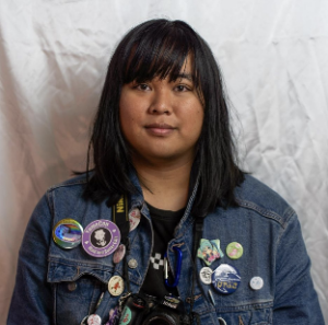 Woman from mid body up with jean jacket on against plain background